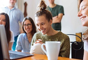 Gruppe junger Leute am Laptop, lachend